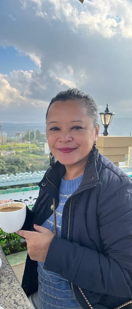 Iadashisha Umwi with a cup of coffee, the Shillong hills behind her